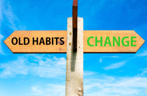 Wooden signpost with two opposite arrows over clear blue sky, Old Habits versus Change messages, Lifestyle change conceptual image