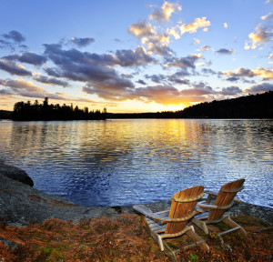 Wooden chair on beach of relaxing lake at sunset in Algonquin Park, Canada